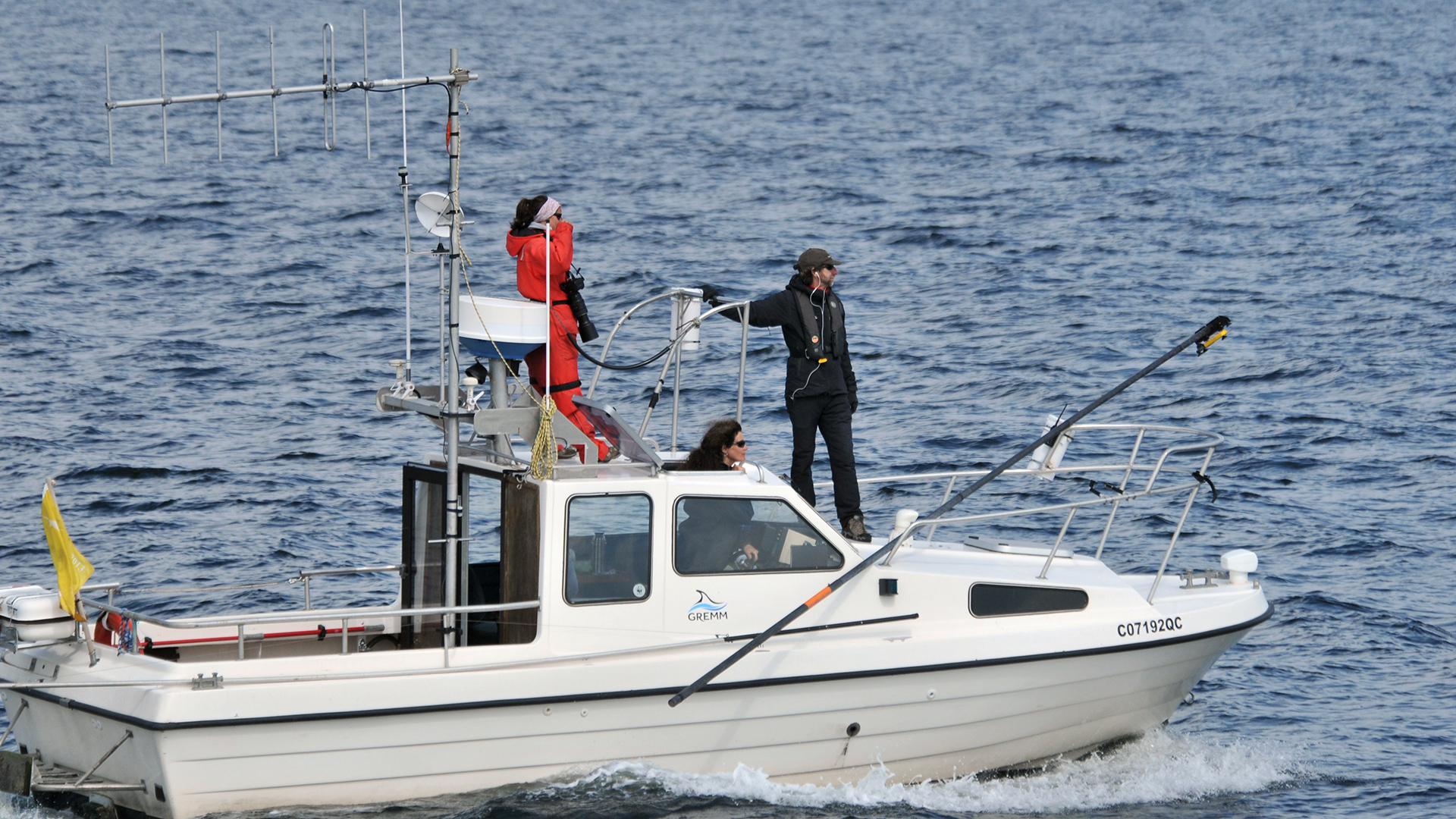 Research boat with three crew members and their tracking tools.
